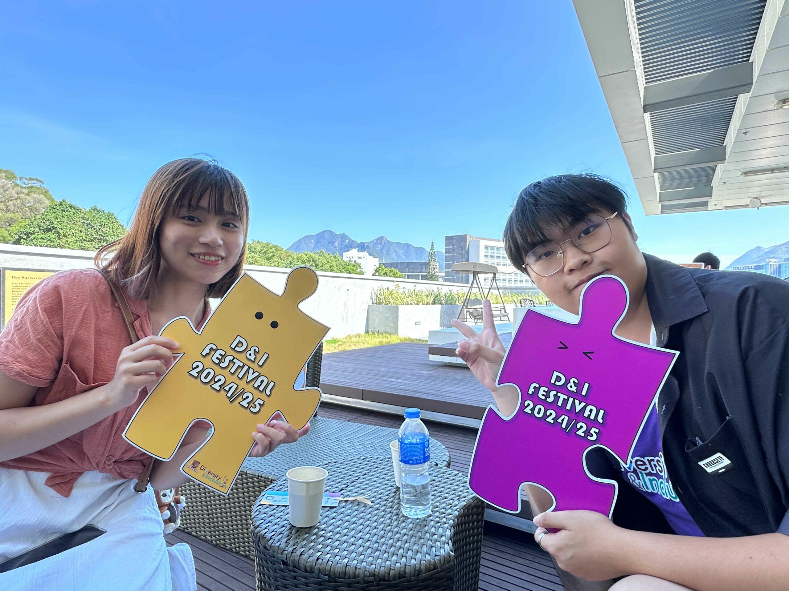 The D&I ambassador and a participant are holding colorful props promoting D&I festivals, smiling.